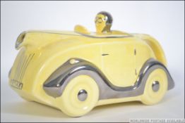 A Sadler novelty racing car teapot number 820236 with a yellow glaze and silver highlights,