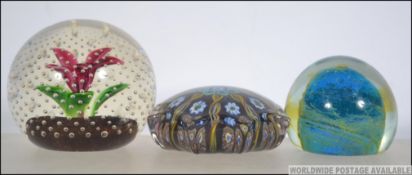 A group of three paperweights to include a medium sized Scottish weight with floral designs,