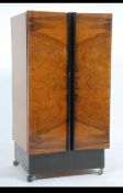 A 1930's Art Deco walnut cabinet with inverted doors having later shelved interior being raised on