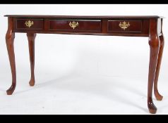 An antique style mahogany console - hall table raised on shaped legs with twin drawers and brass