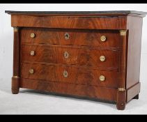 A 19th century French mahogany and black marble empire commode chest of drawers being raised on
