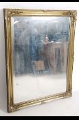 An antique Victorian style gilt overmantel mirror dating to the 20th century having central mirror