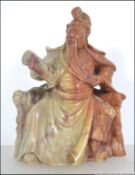 A 20th century Japanese soap stone carving of a seated scholar studying a scroll.
