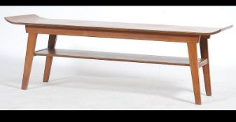 A surfboard style mid century Danish influence teak coffee table raised on tapered angled supports.
