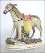 A 19th century Staffordshire figurine flat back of a donkey being raised on a plinth base.