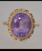 A hallmarked 9ct gold ring set with a central bezel set purple stone. Hallmarked Birmingham. Size L.