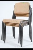 A stack of four vintage industrial tubular grey metal framed stacking chairs with ply seats and