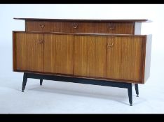 A 1970's G-Plan librenza pattern sideboard having an ebonised base with cupboards and drawers to