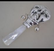 A sterling silver babies rattle with mother of pearl mouthpiece.