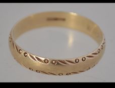 A 9ct hallmarked gold band ring weighing 3.5g having scroll work borders.