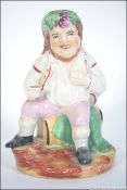 A 19th century Staffordshire figurine of a gentleman seated drinking on a barrel. Unmarked.