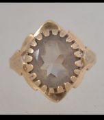 A hallmarked 9ct ring set with a prong set stone with foliate shoulders. Hallmarked London. Size L.