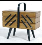 A 1950's metamorphic sewing box raised on tapered legs with multi opening action and central handle.