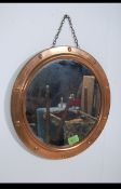 A vintage mid 20th century brass porthole style wall mirror with stud affect surround and metal