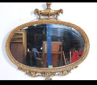 A good 20th century Adams revival gilt mirror of oval form with stunning urn and swag adorned top