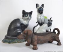 Three Cast iron pieces 2 cold painted doorstops in the form of cats along with a sausage dog boot