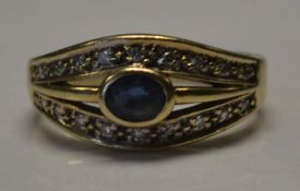 A 9ct gold sapphire and diamond ring set with a central oval cut sapphire with twin diamond set