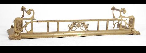 A 19th century fire fender of brass form and in the Art Nouveau manner having curb base with