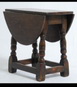 An early 20th cenutry solid oak drop leaf coffin / butterfly side table being raised on block and