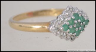 A 9ct gold emerald and diamond ring having cluster emeralds with diamond surrounds.