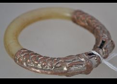 A Chinese jade mutton fat coloured bangle with copper twin headed dragon top