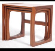 A 1970's retro G-Plan Kelso nest of tables being raised on squared legs with peripheral stretchers,