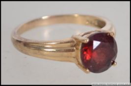 A 9ct gold ring stamped 375 set with a single large round cut garnet in a prong setting.