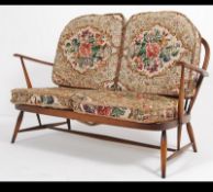 An Ercol beech and elm wood Windsor pattern two seat sofa settee raised on turned legs with