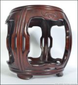 A 20th century Chinese hardwood opium barrel stool with carved details having open sides and bottom