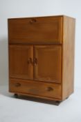 A retro Ercol elm wood retro bureau - drinks cabinet in the Windsor pattern having chamfered detail