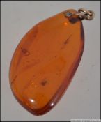 An early 20th century large amber pendant, with insect inclusions having a 9ct gold mount.