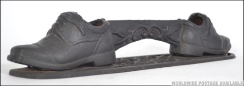 A vintage early to mid 20th century cast iron boot scrape in the form of a pair of boots united by