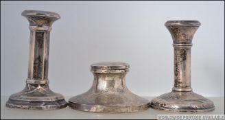 A near pair of silver filled stub stub candle sticks along with a silver capstan ink well.