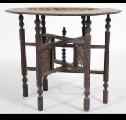 An Anglo Indian late 19th early 20th century enamel and brass tray top table on folding carved