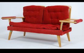 A 1950's retro mid century two seat sofa settee raised on tapered legs with unusual table elbow