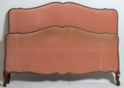 An early 20th century French corbeille bed with pink fabric upholstered head and footboard united