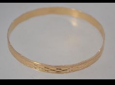 A hallmarked 9ct gold bangle with scalloped edges and diamond cut star engraving. Hallmarked London.