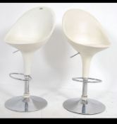 A pair of 20th century Dwell white leather and chrome retro modernist bar stools raised on gas