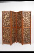 An early 20th century Arts & Crafts solid oak four fold dressing screen having applied gilt panel