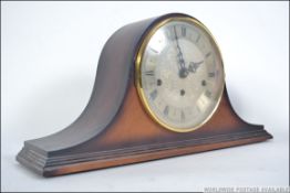 A mid century napoleons hat oak mantel clock by St James of London having silvered dial with