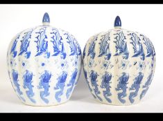 A pair of 20th century blue and white lidded ginger jars of large form decorated with foliage and