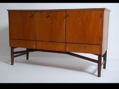 A retro 20th century teak wood sideboard in the manner of Gordon Russel having chamfered top above