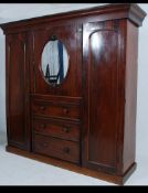 A Victorian mahogany triple wardrobe having a central chest of drawers under a mirror door cupboard