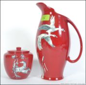 A Crown Devon Fieldings ceramic jug with a Rouge ground adorned with white Swans together with a