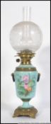 An early 20th century oil lamp rasied on a circular base with feet with a painted ceramic body and