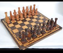 A 20th century contemporary carved wooden chess set of Asian / Chinese origin stored within a it's