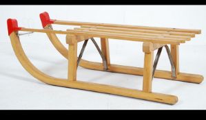 A vintage style 20th century wooden sledge with slated wooden seat raised on metal lined runners.