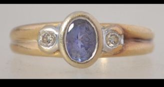 A 14ct gold ring set with a central blue stone with diamond accents and fluted shoulders.