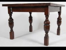 An early 20th century oak draw leaf refectory dining table raised on block and turned legs with