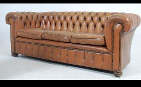 A 20th century brown leather chesterfield sofa settee with barrel arms and back rest having
